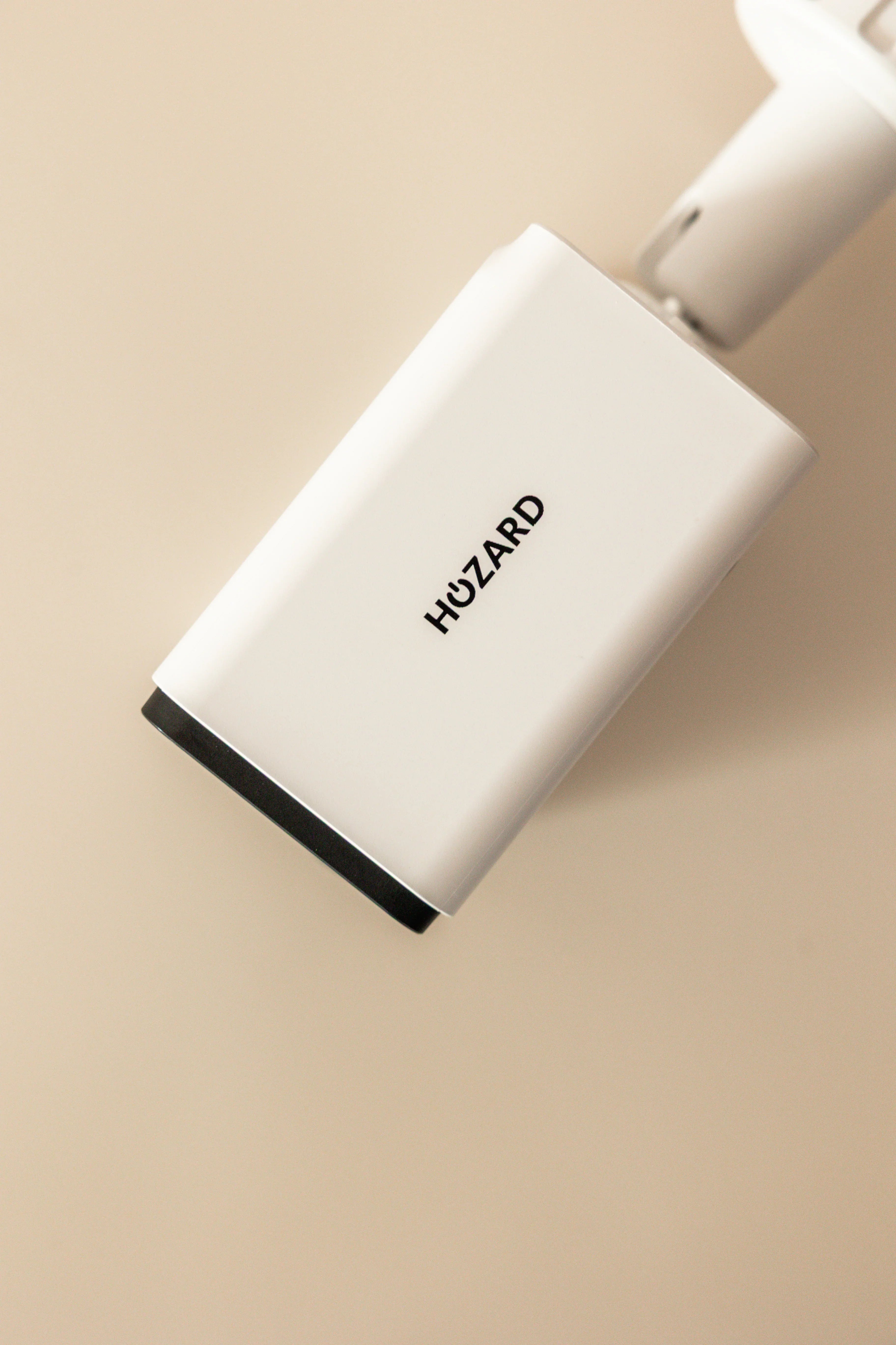 Witte beveiligingscamera met Hozard-logo, close-up tegen beige achtergrond