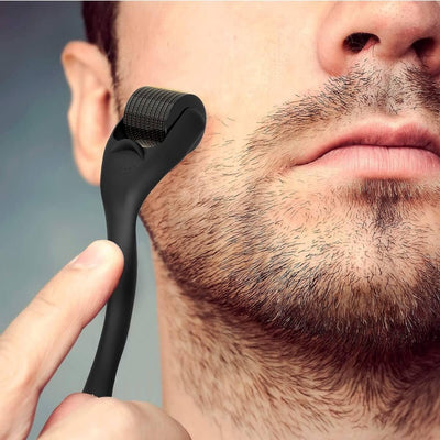 Man gebruikt een zwarte dermaroller op zijn baard, microneedling voor baardgroei