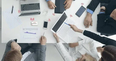 Zakelijk overleg met laptops, smartphones en elektronica op modern kantoor, draadloze connectiviteit zichtbaar.