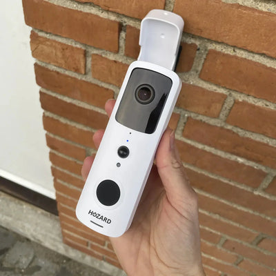 Draadloze video deurbel met camera en intercom, vastgehouden voor bakstenen muur