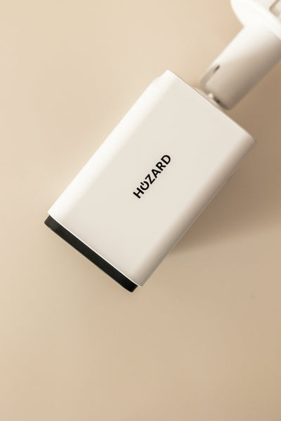 Witte beveiligingscamera met Hozard-logo, close-up tegen beige achtergrond